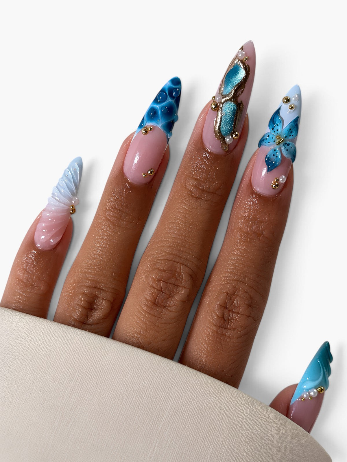Manucure Cherry Rouge Azure Shell stiletto avec coquillages 3D, fleurs bleues, perles et détails dorés nacrés.
