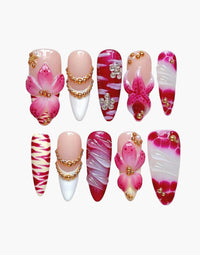 Manucure Cherry Rouge Blooming Luxe en forme amande avec fleurs 3D roses, détails dorés, marbré et ornements bijoux.