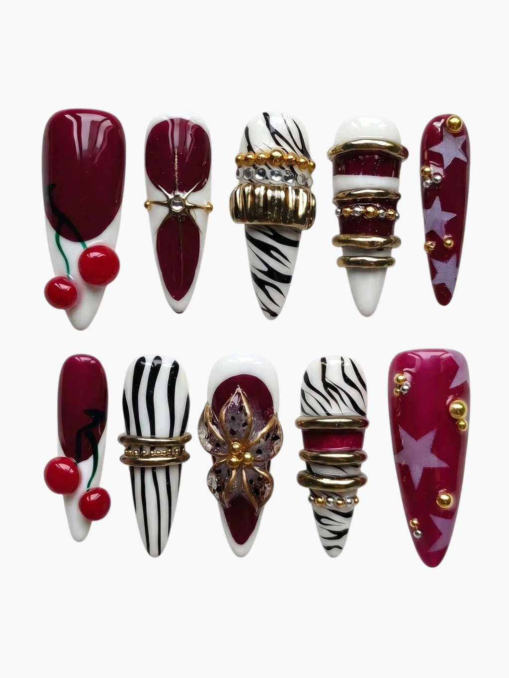 Press-on nails Cherry Rouge Cherry Mirage en forme amande, motifs cerises, zébrés, étoiles et détails dorés en relief.