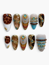 Set de 10 faux ongles Cherry Rouge forme amande avec motifs organiques, détails dorés, strass bleus et effets nacrés.