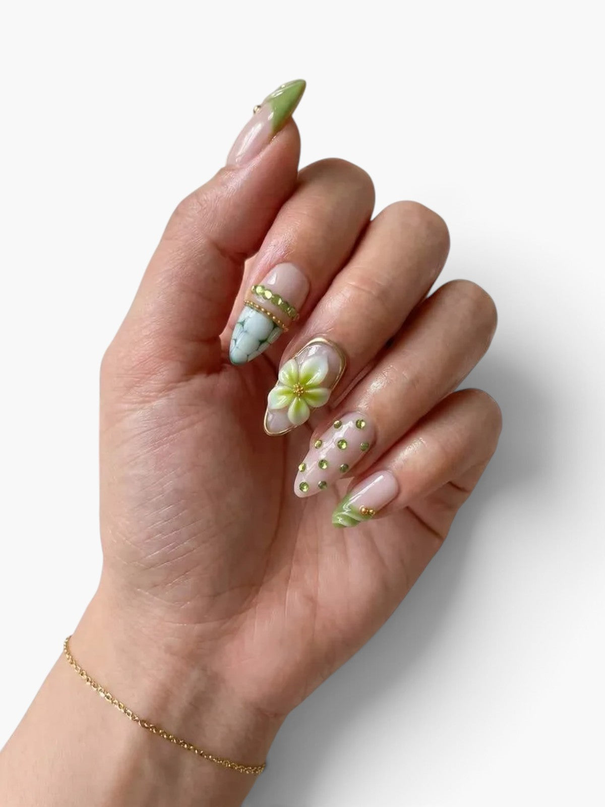 Main portant des faux ongles Cherry Rouge en forme amande, décorés de motifs floraux, marbrés et strass vert pastel.