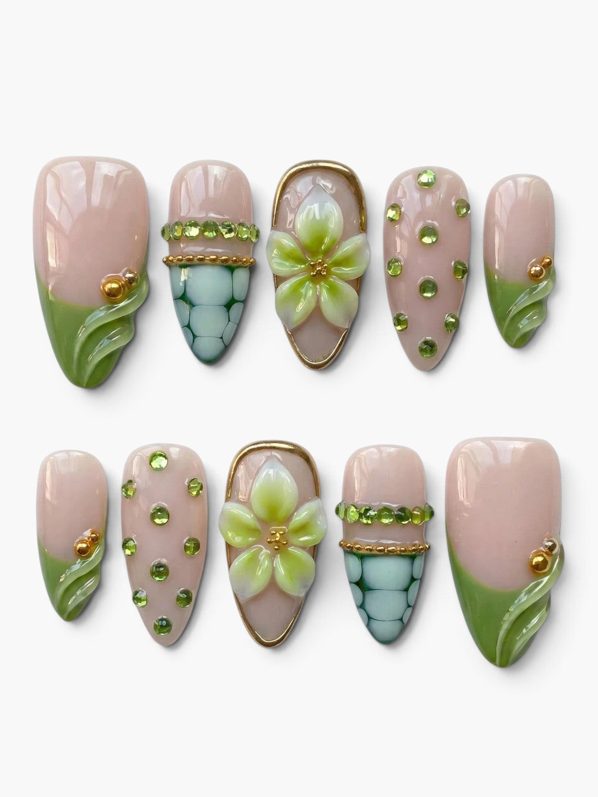 Set de 10 faux ongles Cherry Rouge en amande, base nude rosée avec motifs floraux 3D, strass verts et détails dorés.