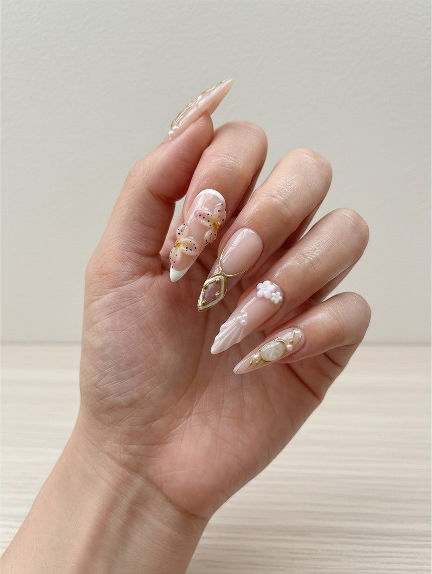 Faux ongles Cherry Rouge longs en amande avec motifs floraux, perles et détails dorés style Y2K sur une main