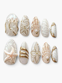 Set de 10 faux ongles Cherry Rouge Amber Tide en forme amande avec motifs marins, coquillages, perles et détails dorés