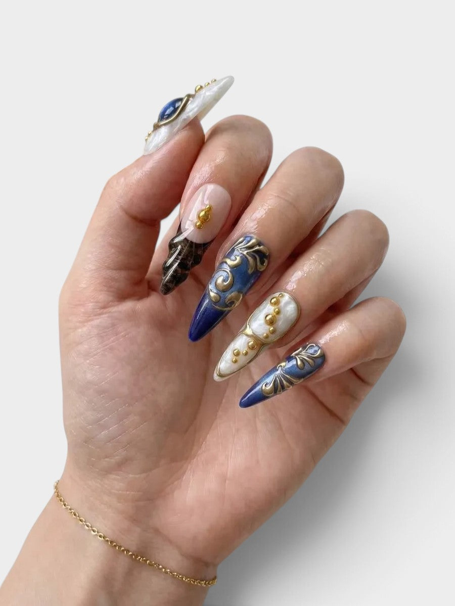 Main Cherry Rouge She’s Royal avec faux ongles pointus en gel bleu marbré, détails dorés en relief et motifs léopard.