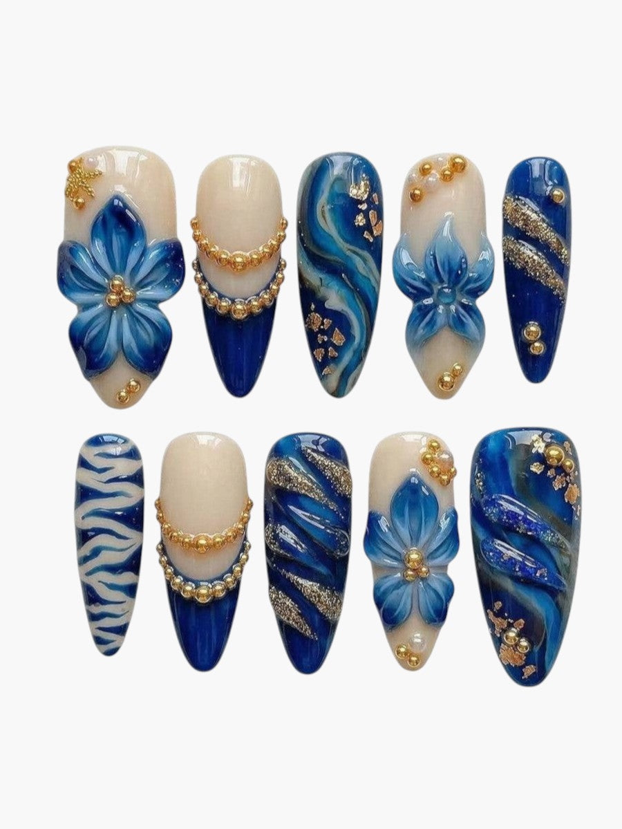 Set de 10 faux ongles Cherry Rouge Blooming Luxe forme amande, bleu et nude avec fleurs 3D, détails dorés et marbrés.