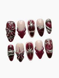 Set de 10 faux ongles Cherry Rouge en forme amande, gel bordeaux et nude avec ornements dorés et motifs étoilés.