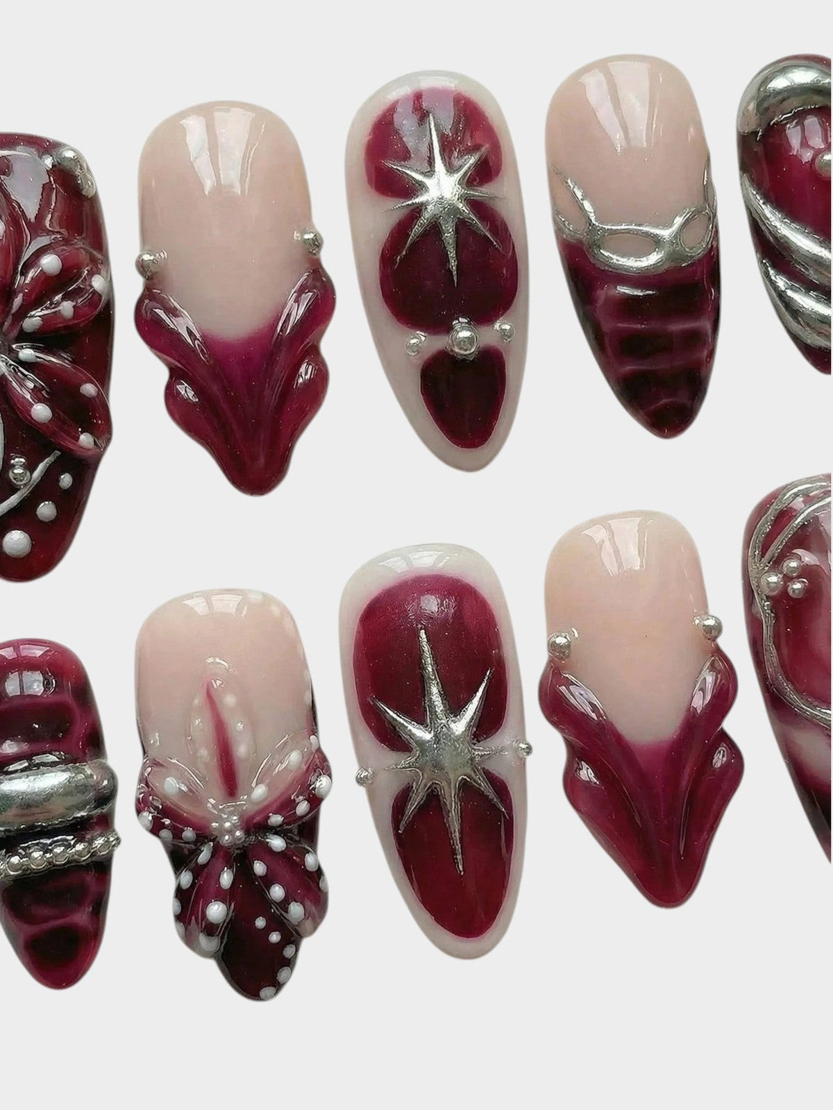Faux ongles Cherry Rouge Dewdrop Romance avec motifs bordeaux, détails argentés en relief et étoiles scintillantes.