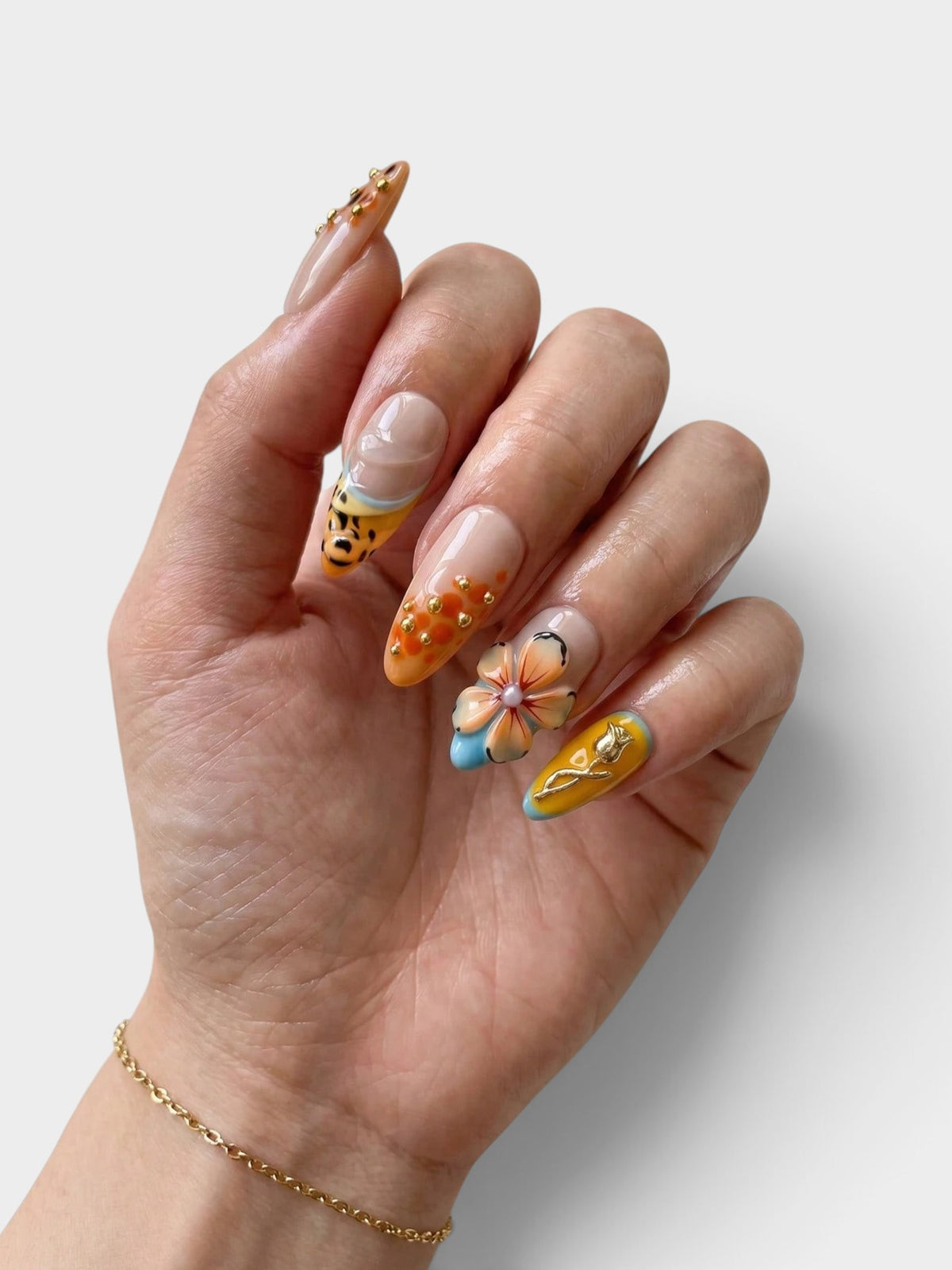 Main Cherry Rouge ornée de faux ongles Leopard Petal Gold avec motifs léopard, fleurs sculptées et détails dorés