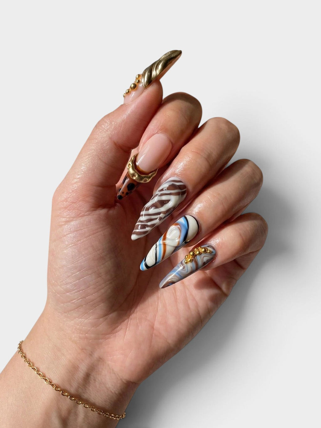 Main Cherry Rouge She’s Royal avec faux ongles pointus longs, motif marbré bleu, détails dorés et reliefs 3D léopard.
