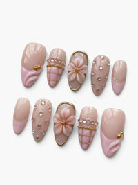 Set de 10 faux ongles Cherry Rouge en forme amande, couleur nude rosé translucide avec fleurs en relief et strass.