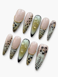 Set de 10 faux ongles Cherry Rouge Dream Girl forme stiletto, nude rosé et parme avec fleurs 3D et détails dorés.