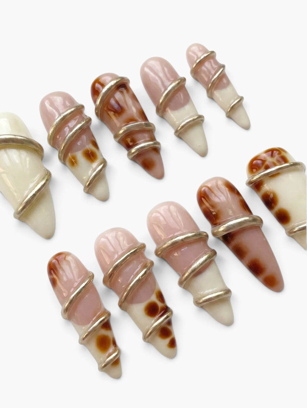 Cherry Rouge Gilded Twist : faux ongles amande en gel beige nude, blanc crème et motifs écailles avec torsades dorées.