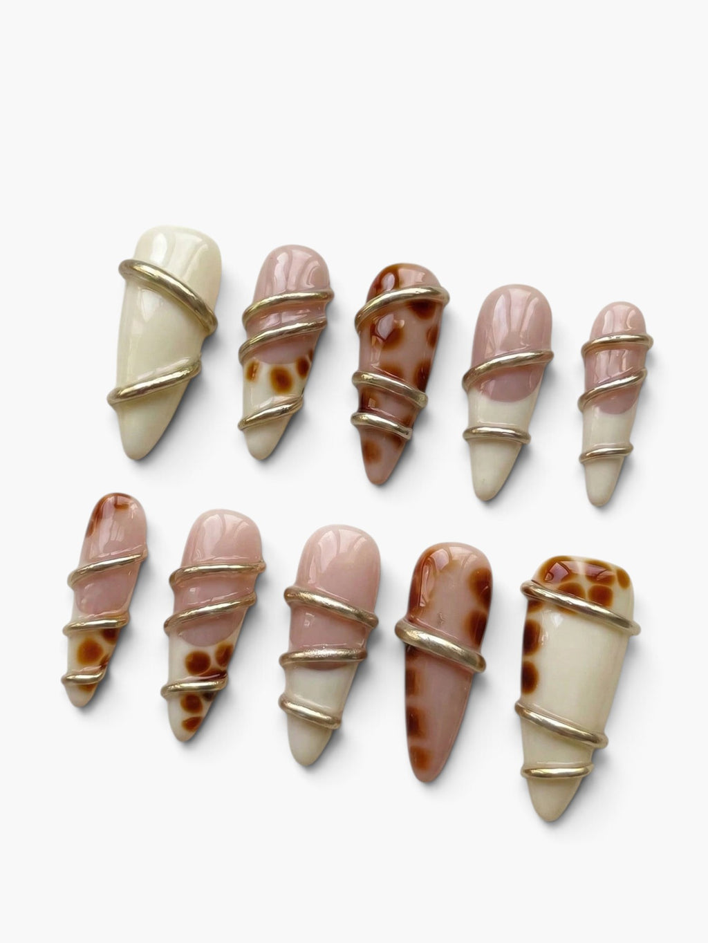 Manucure Cherry Rouge Gilded Twist en forme amande, gel beige nude et crème avec des torsades dorées brillantes.