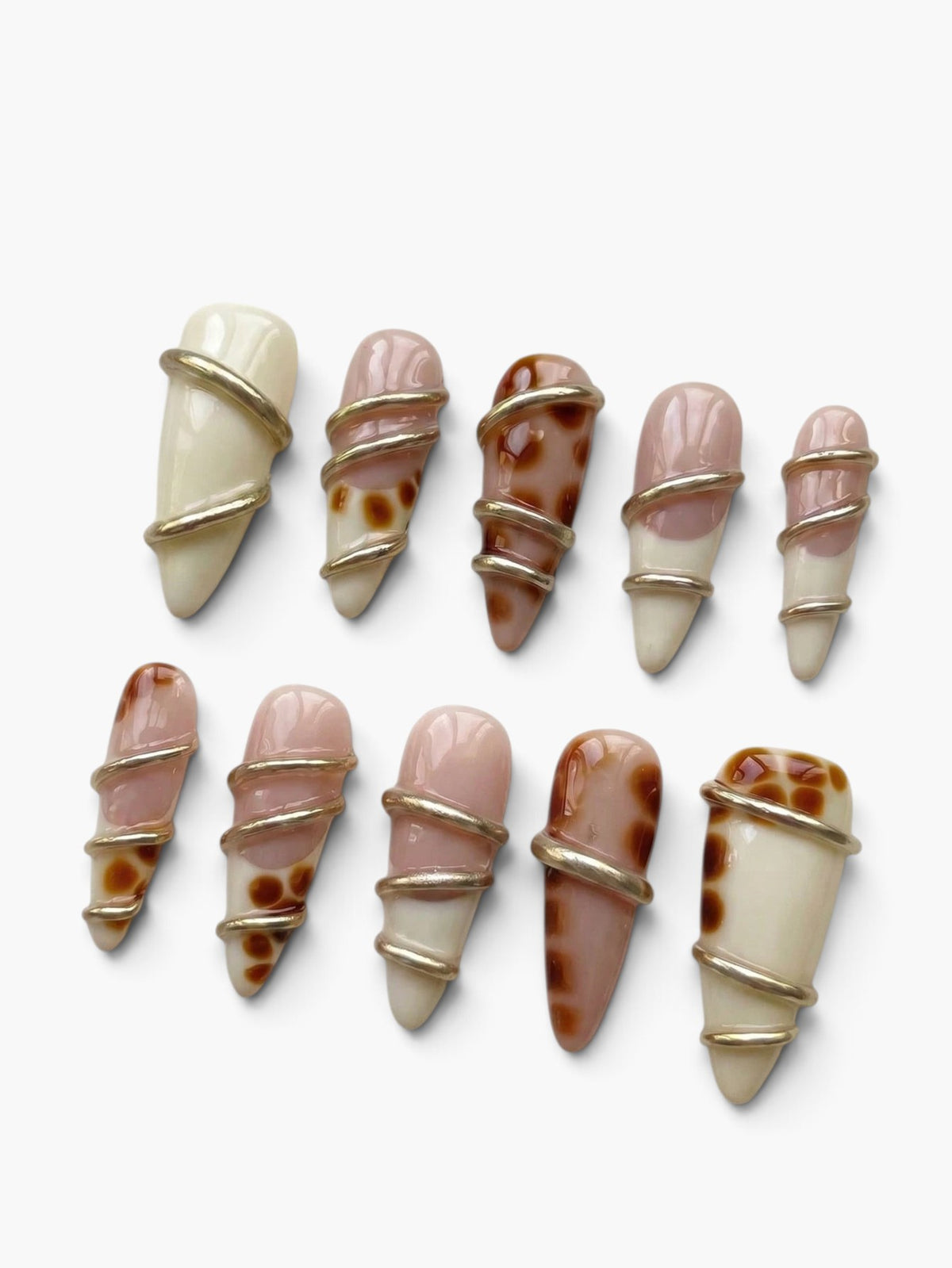 Manucure Cherry Rouge Gilded Twist en forme amande, gel beige nude et crème avec des torsades dorées brillantes.