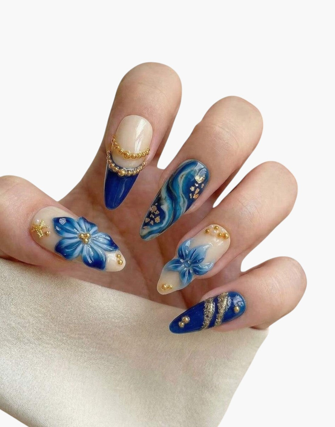 Manucure Cherry Rouge Blooming Luxe en forme amande avec fleurs 3D bleues, détails dorés et effet marbré sur base nude