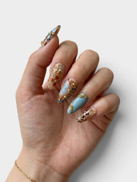 Manucure Cherry Rouge Bohemian Leopard Kiss en forme amande avec motifs léopard, détails dorés et finition brillante