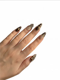 Manucure Cherry Rouge Dewdrop Romance avec ongles longs en amande, motifs floraux marron, dorés et détails perlés