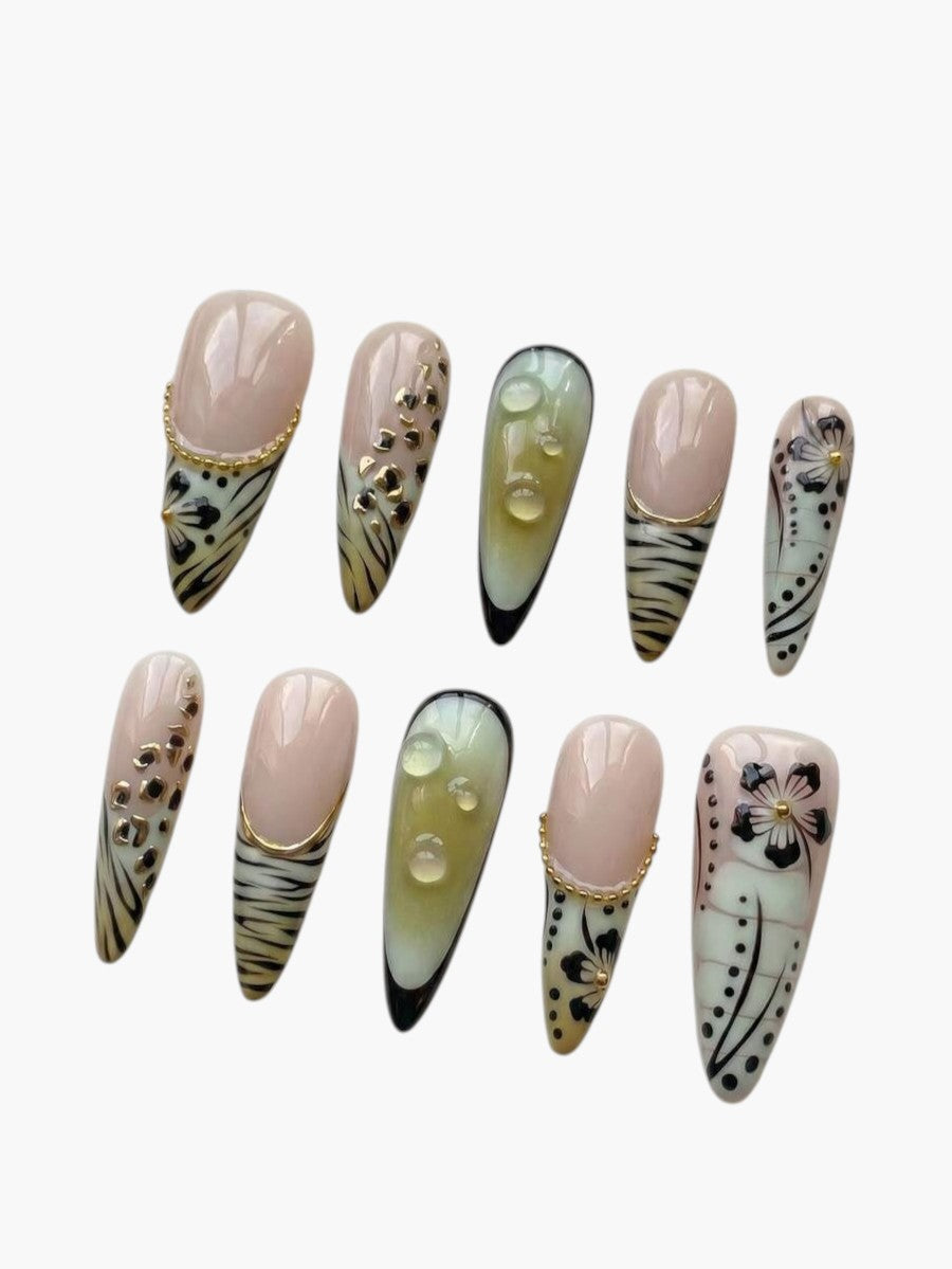 Faux ongles Cherry Rouge longs en amande style Y2K avec motifs de silhouettes végétales, détails dorés et effet gel.