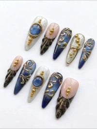 Press-on nails Cherry Rouge She’s Royal en gel bleu marbré, motifs léopard, détails dorés 3D et finition brillante.
