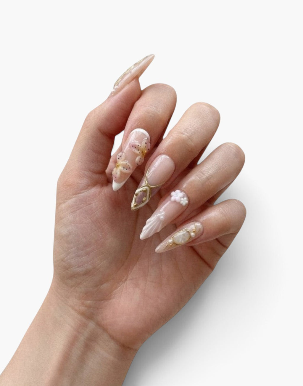 Manucure Cherry Rouge She’s Fancy stiletto nude avec fleurs 3D, détails dorés et motifs texturés sur ongles longs