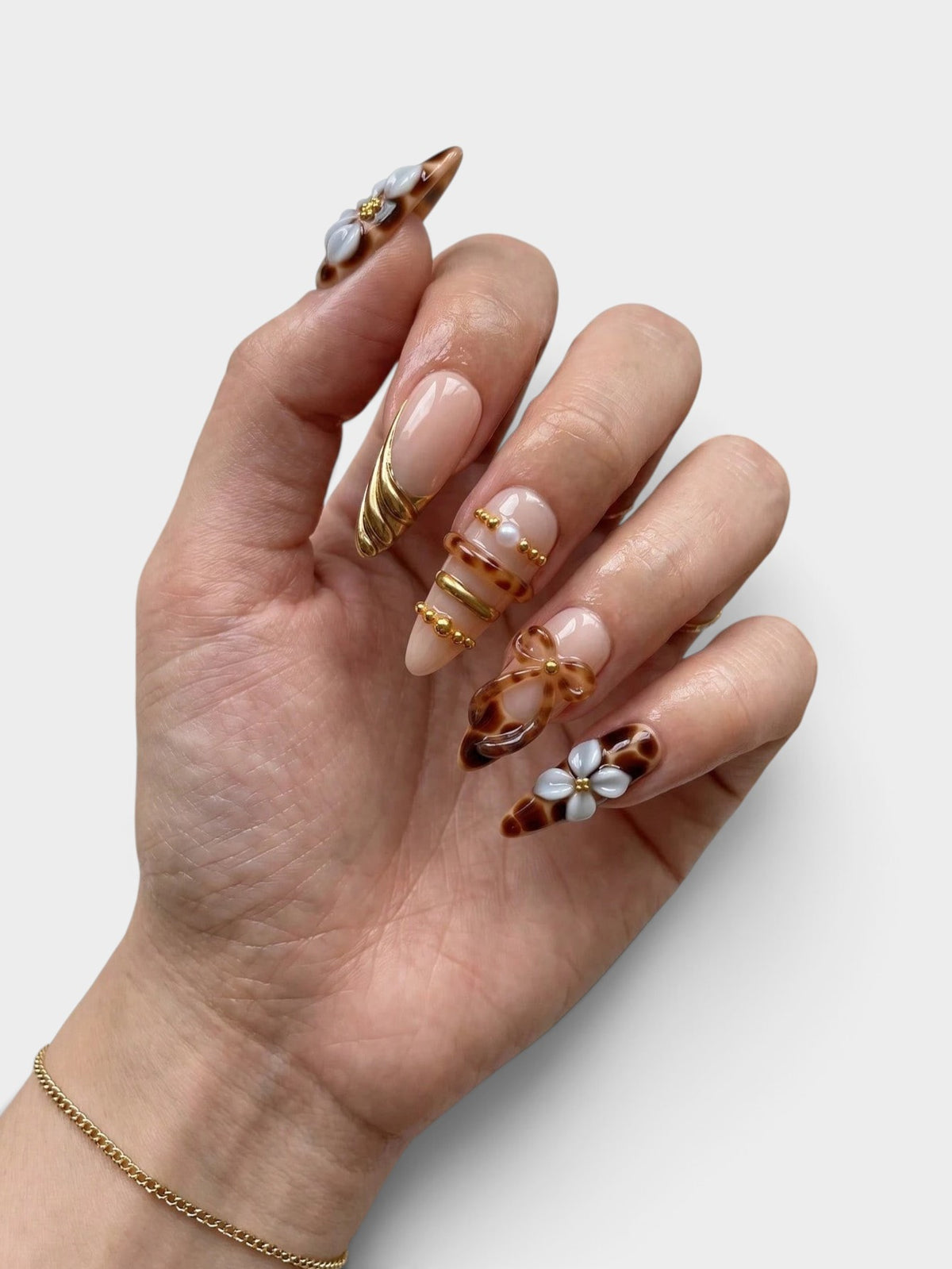 Main Cherry Rouge Tortoise Petals en forme amande avec motifs écaille de tortue, fleurs sculptées et détails dorés.