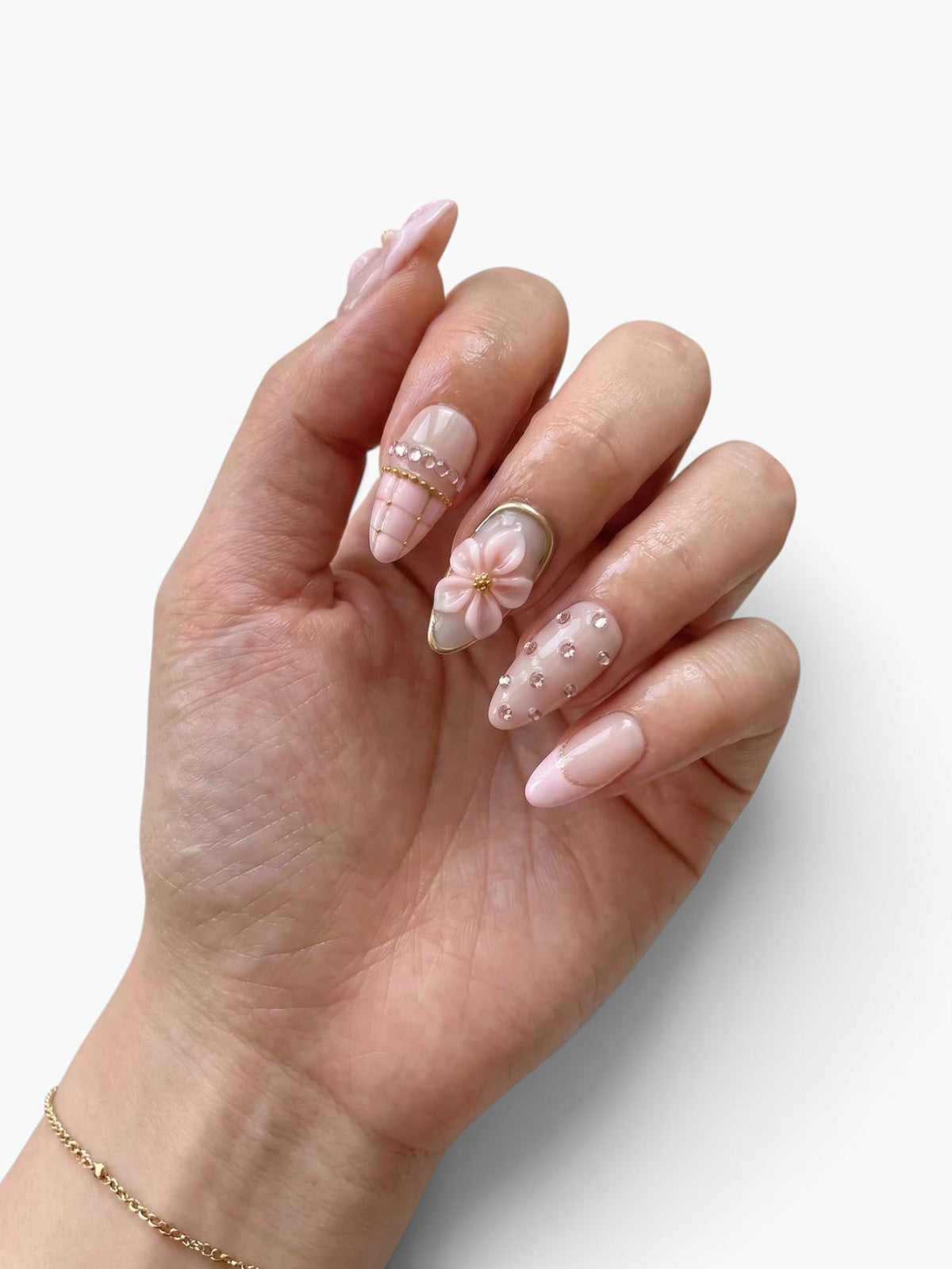 Main portant des faux ongles Cherry Rouge Rosé Radiance en forme amande, nude rosé avec fleurs 3D et strass brillants